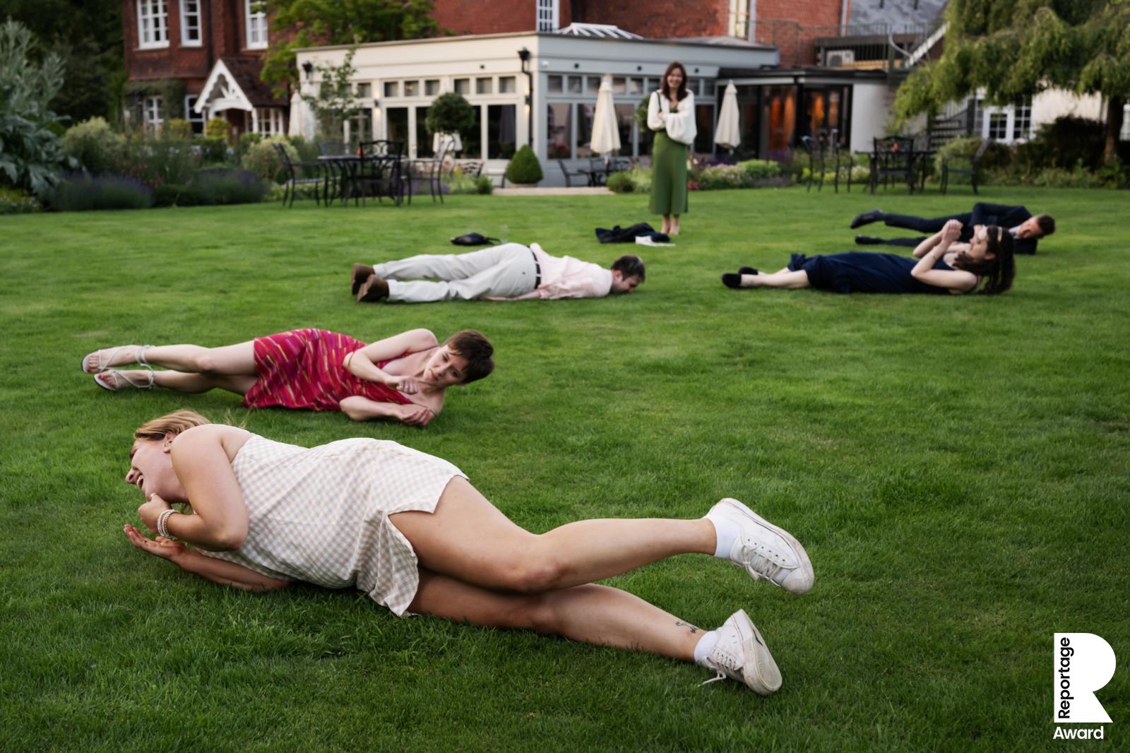 Wedding guests laughing and rolling on the grass at The Barns at Redcoats