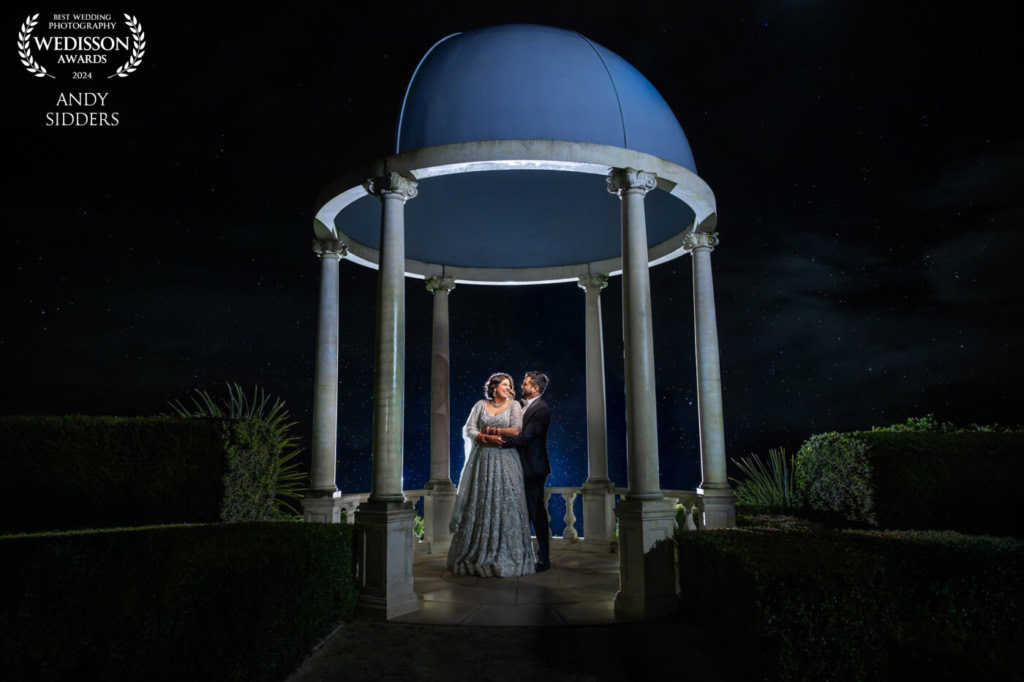 A night-time portrait of the bride and groom under the gazebo at Froyle Park