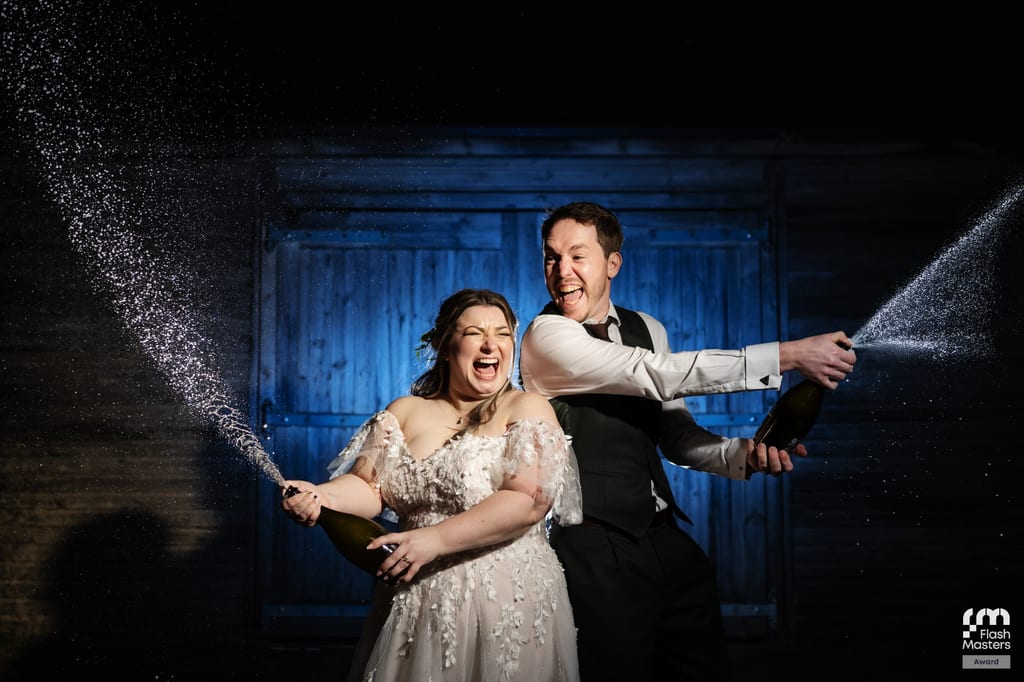 Bride and groom spraying champagne together at Stratton Court Barn