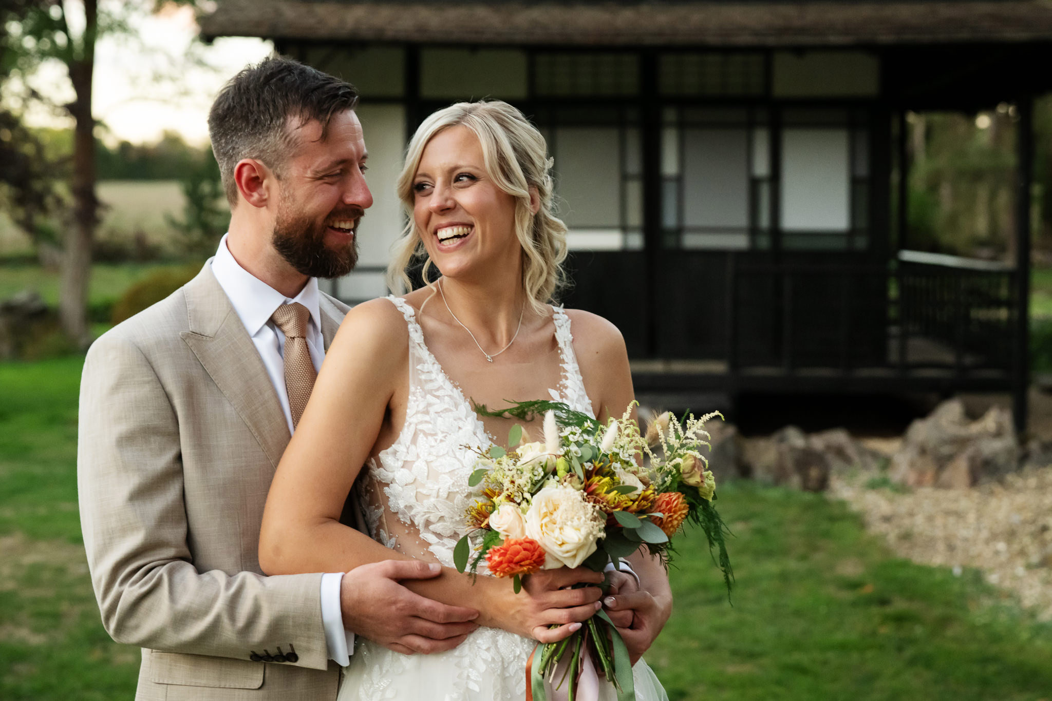 Bride and groom laughing together outside the Japanese Tea House at Fanhams Hall in Hertfordshire